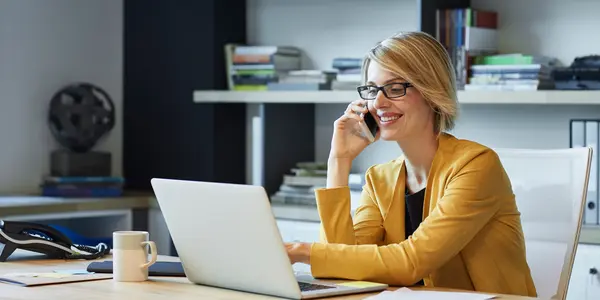 Kvinna vid dator pratar i telefon